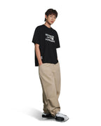 A young man modeling a black short-sleeve graphic t-shirt with white text that reads 'BEWARE OF CROWD HUMANS', paired with beige baggy cargo pants and black-and-white sneakers, set against a plain white background.