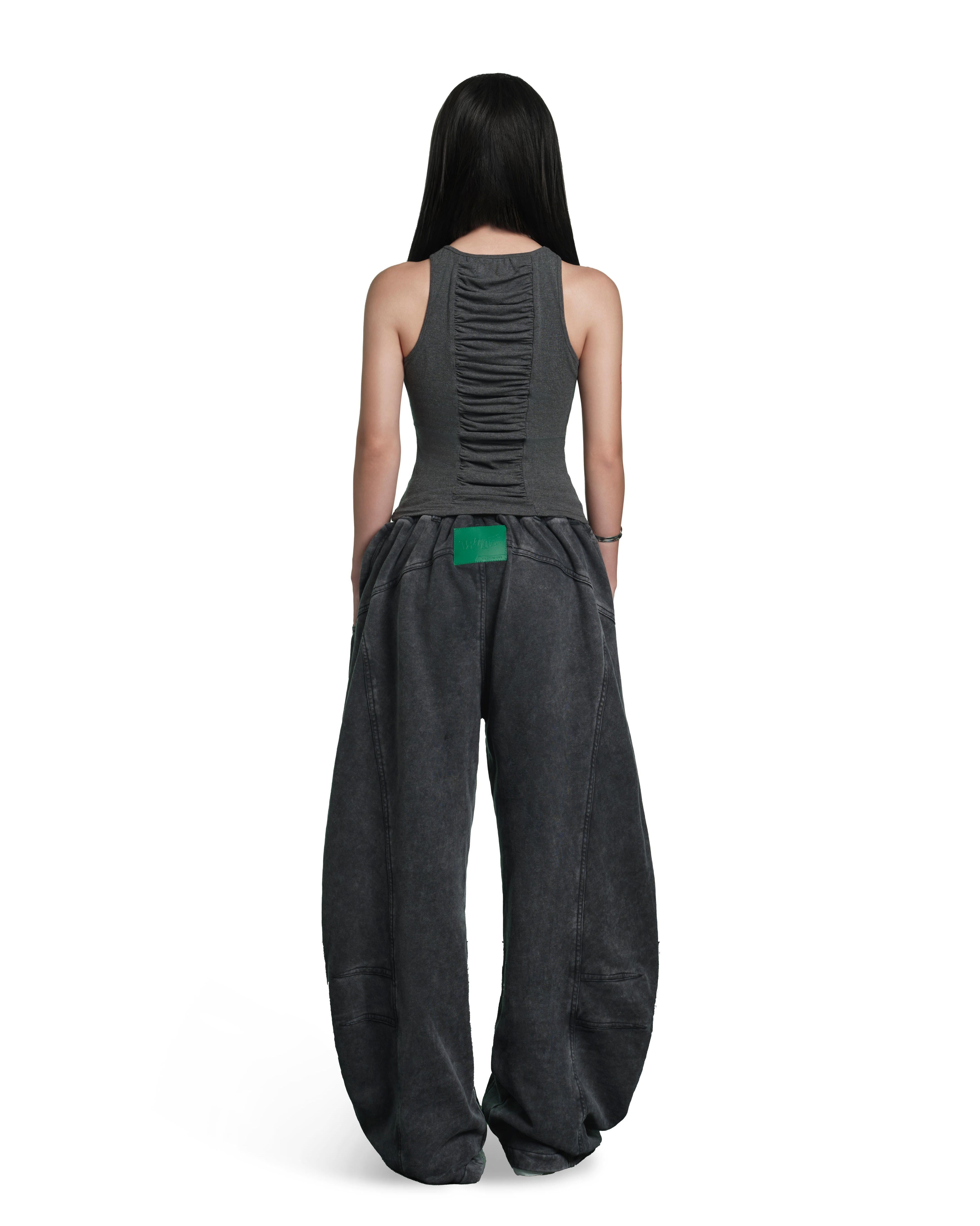 A model shown from the back wearing a dark gray sleeveless top with a ruched back and matching wide-leg pants, featuring a bright green accent patch at the waist, on a solid white background.