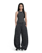 A model stands against a solid white background wearing a dark gray ribbed sleeveless top and matching dark gray wide-leg pants with a washed texture.