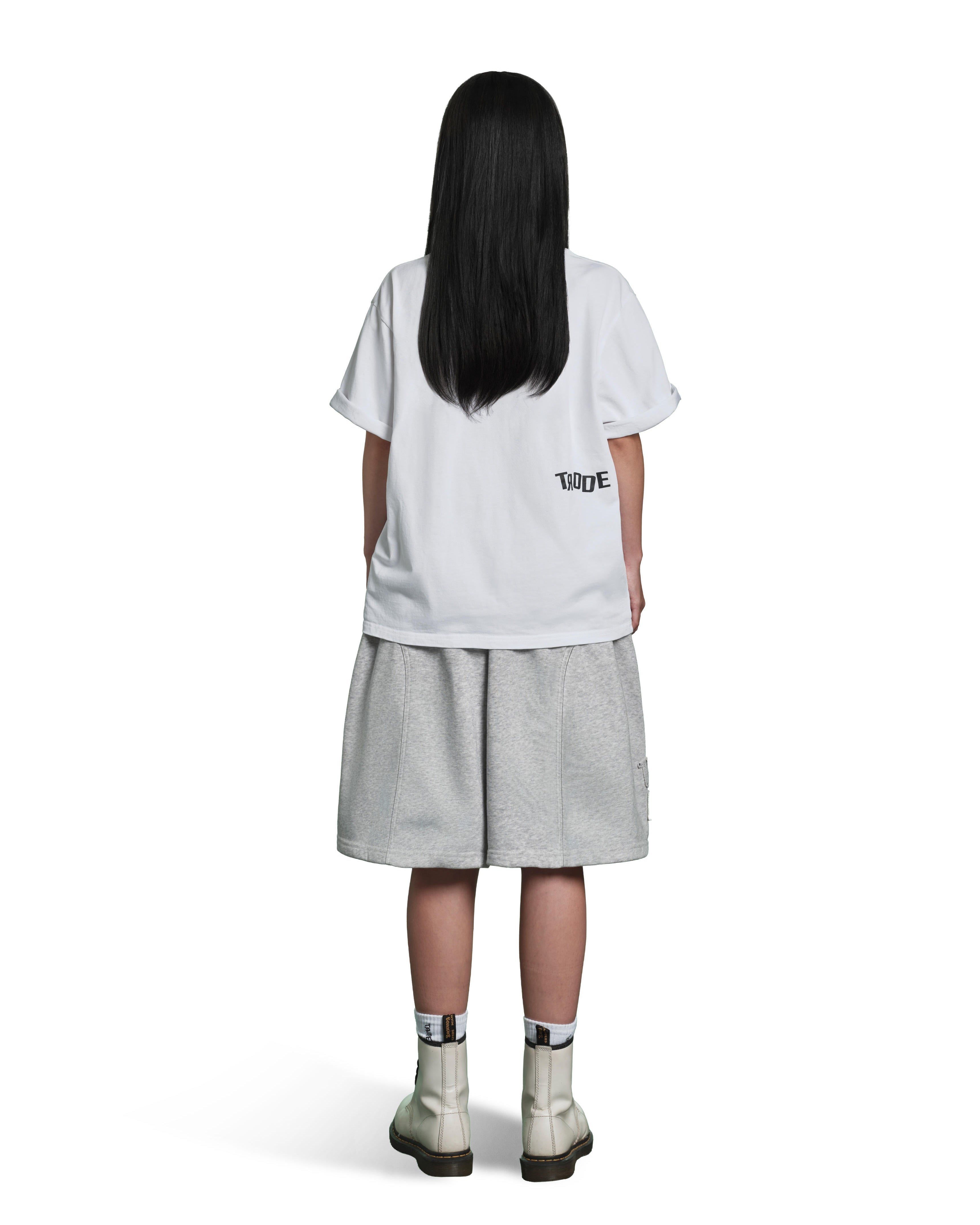 A child model shown from the back wearing a white oversized T-shirt with a small black 'TIDE' logo on the left side, light gray shorts, and off-white ankle boots, against a plain white background.